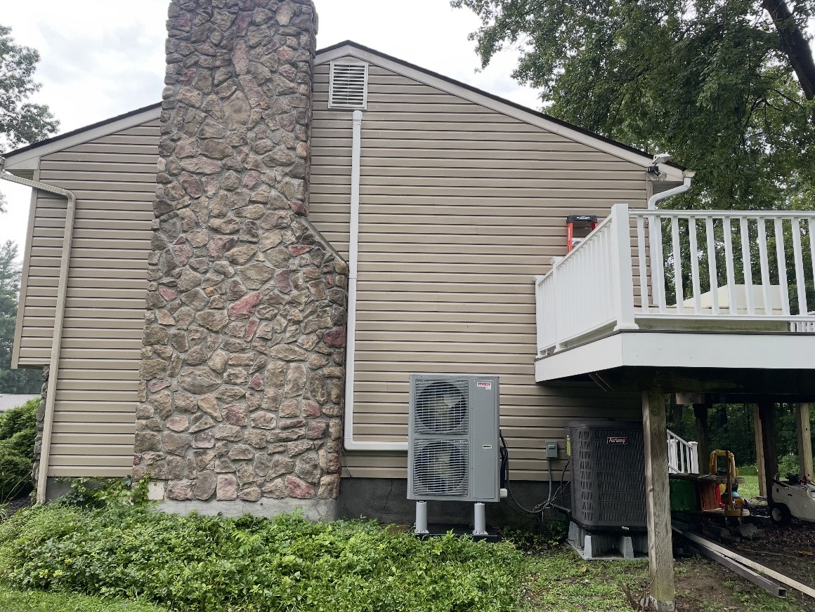 Clean tan vinyl siding next to a stone chimney