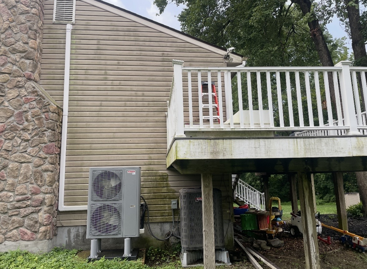 Tan vinyl siding with green algae and dirt buildup