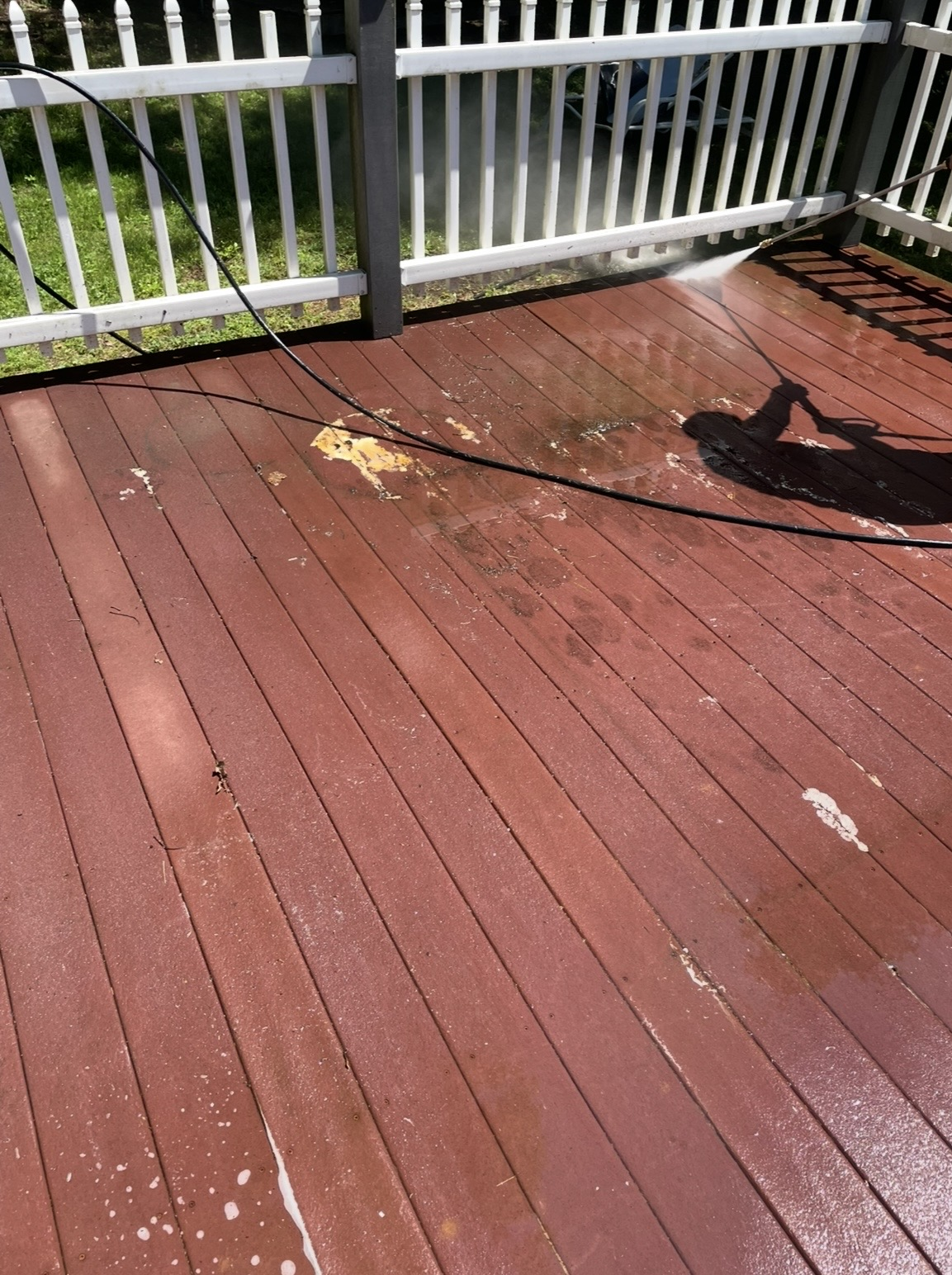 Stripping old paint from a wooden deck with a pressure washer